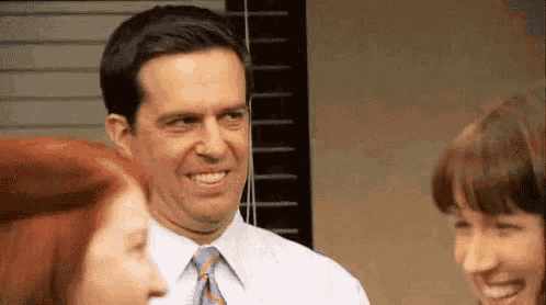 a man in a suit and tie is talking to two women in an office .