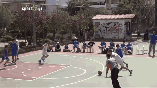 a basketball game is being played in front of a sign that says sport 5 gr