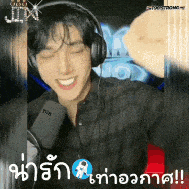 a man wearing headphones is smiling in front of a microphone with the number t98 on it