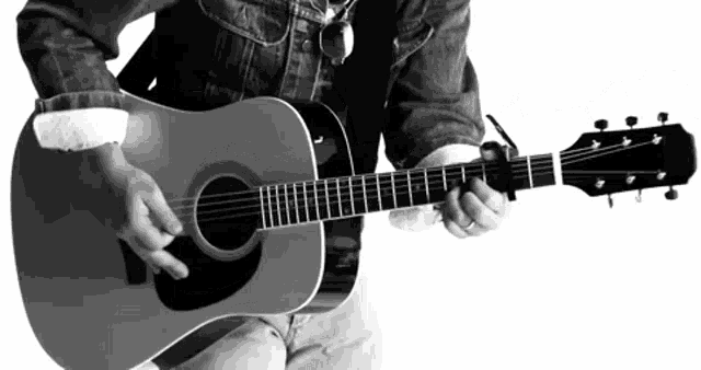 a man in a denim shirt is playing an acoustic guitar in a black and white photo