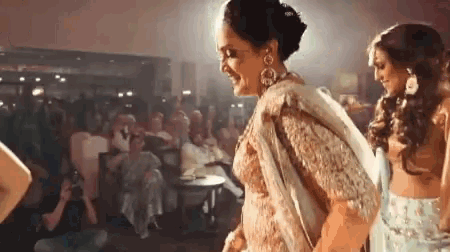 a woman in a sari is dancing in front of a crowd of people .