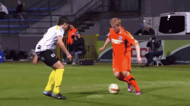 two soccer players on a field with adzmci in the corner