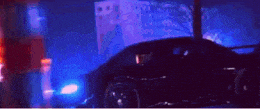 a car is driving down a street at night with a building in the background