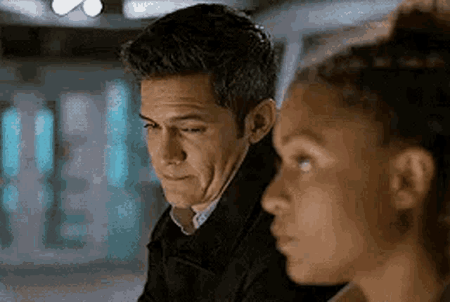 a man and a woman are sitting next to each other looking at something .