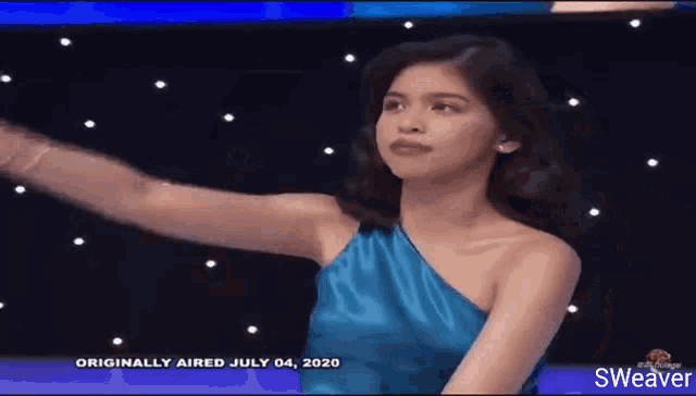 a woman in a blue one shoulder dress is standing in front of a starry sky .