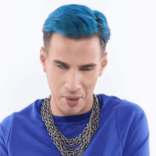 a man with blue hair is wearing a blue shirt and chains around his neck