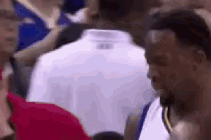 a basketball player is standing in the middle of a crowd of people .
