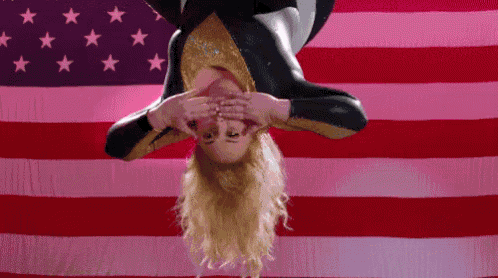 a woman is upside down in front of an american flag covering her eyes .