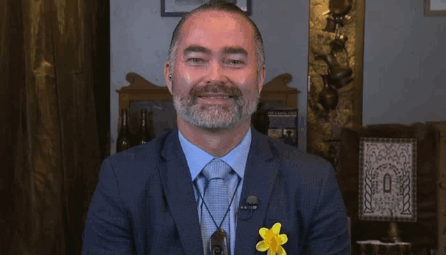a man in a suit has a yellow flower pinned to his jacket