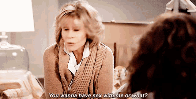 a woman is sitting on a bed talking to another woman and says you wanna have sex with me or what