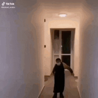 a man wearing a mask is standing in a hallway .