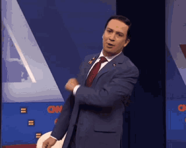 a man in a suit and tie is dancing in front of a cnn logo .