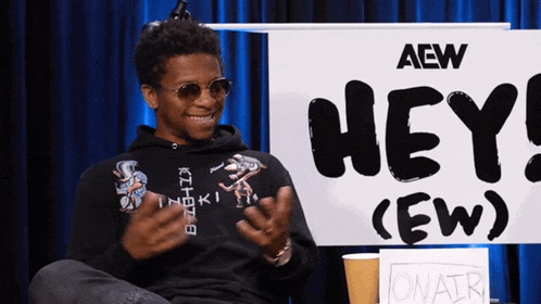 a man is sitting in front of a sign that says hey ew