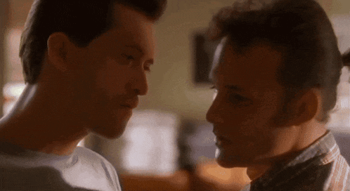 two men are looking at each other 's faces in a room .