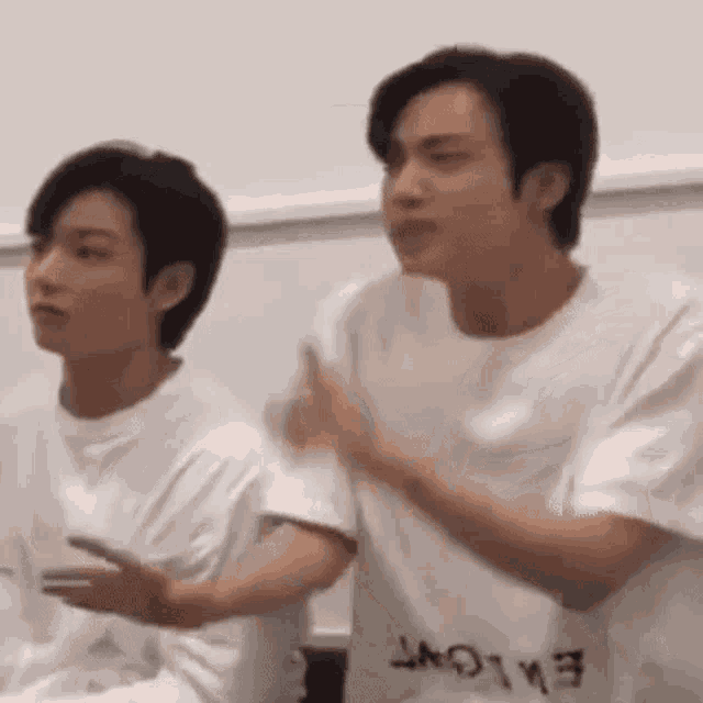two young men are sitting next to each other in a room .