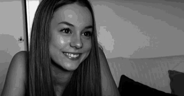 a black and white photo of a smiling woman with long hair
