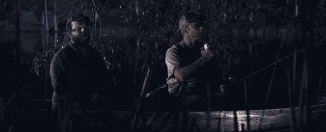 two men are fishing in the dark and one is holding a flashlight
