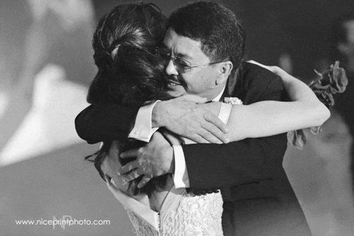 a black and white photo of a man hugging a woman with the website www.niceprintphoto.com visible