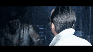 a man in a white shirt looks at his reflection in the mirror
