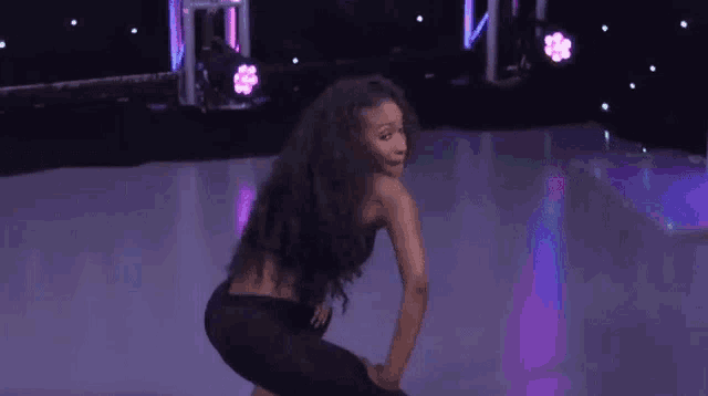 a woman is squatting down on a dance floor .