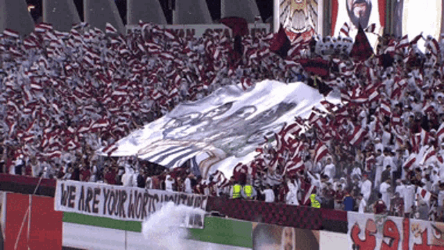 a crowd of people in a stadium with a banner that says we are your warriors