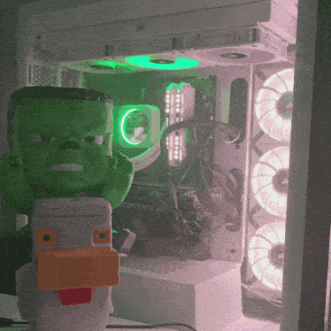 a green hulk figurine sits in front of a corsair rtx 30 motherboard
