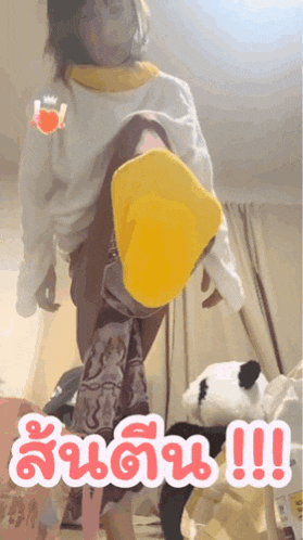 a woman wearing yellow socks is kicking a stuffed animal in a room with chinese writing