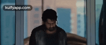 a man with a beard is walking through a glass door .