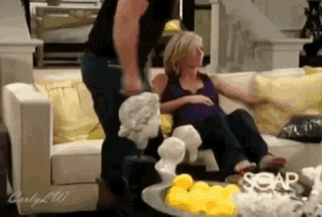 a man is standing next to a woman sitting on a couch
