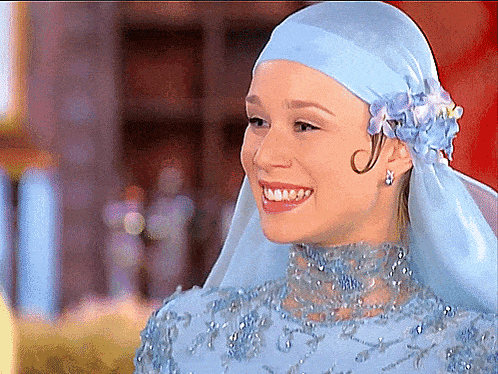 a woman wearing a blue head scarf with flowers on it smiles