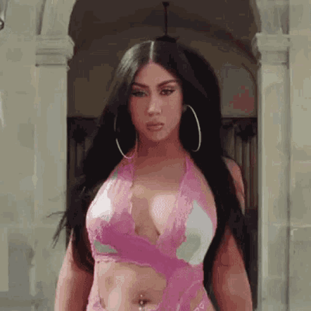 a woman is wearing a pink halter top and hoop earrings .
