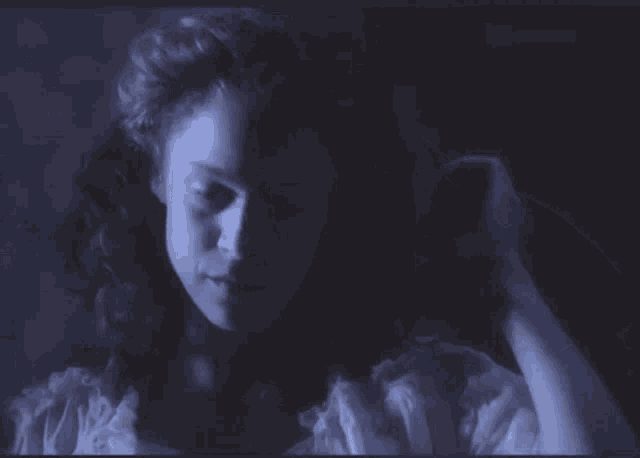 a woman in a white dress is holding her hair in the dark