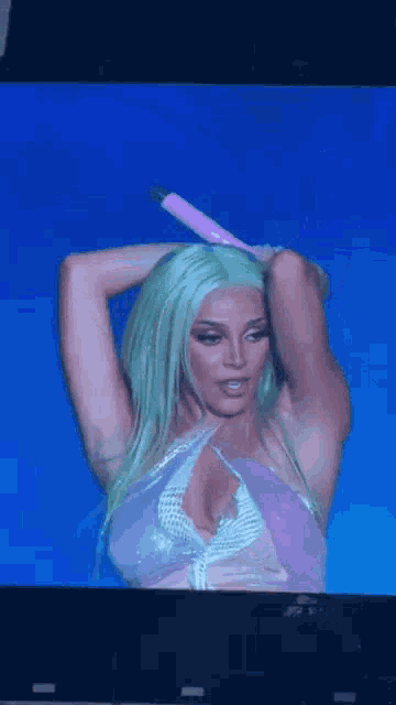 a woman with green hair is holding a pink microphone in her hand while standing on a stage .