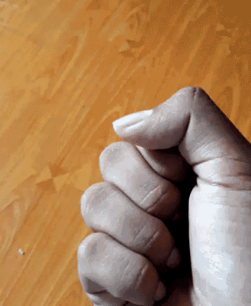 a close up of a person 's fist against a wooden table