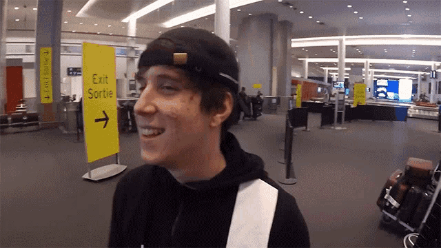 a man is smiling in front of a sign that says exit sortie