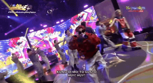 a group of people are dancing on a stage with the words kung di mo to gusto huey huey on the bottom