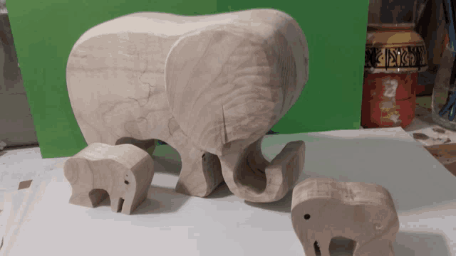 three wooden elephants are sitting on a white surface