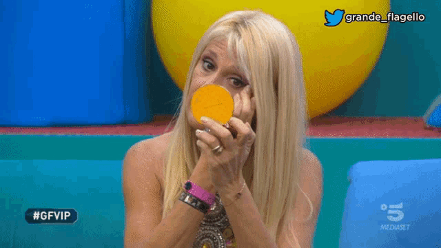 a woman holding an orange in front of her face with the hashtag #gfvip in the corner