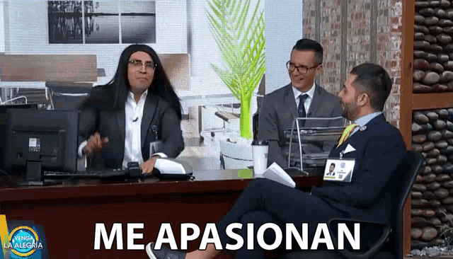 a man in a suit sits at a desk with the words me apasionan below him