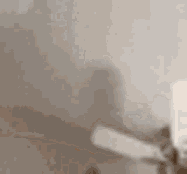 a blurry picture of a person laying on a bed with a white wall in the background .