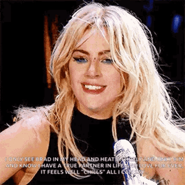 a woman with blonde hair is talking into a microphone .