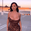a woman wearing a leopard print dress is standing in a parking lot .