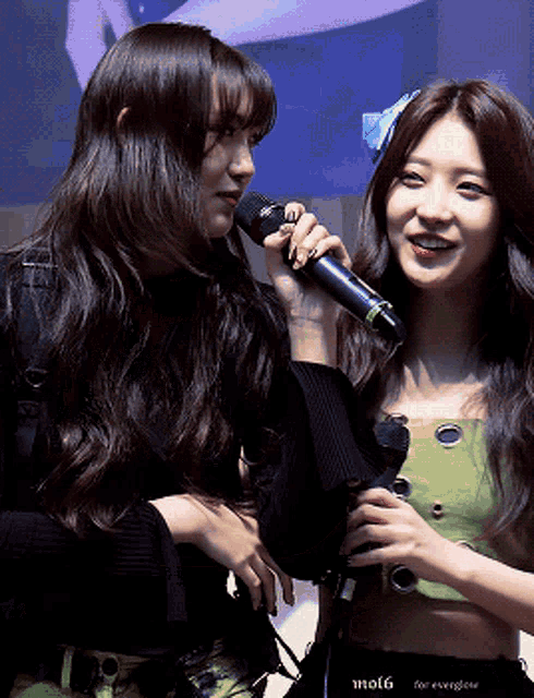 two women are standing next to each other and one is holding a microphone that says mol6