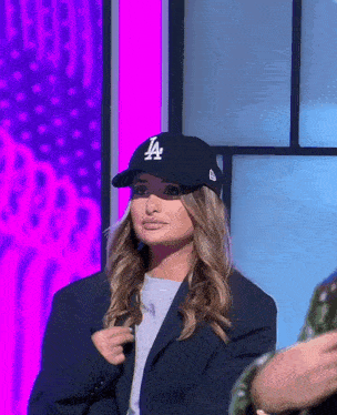 a woman wearing a la baseball cap and a blazer
