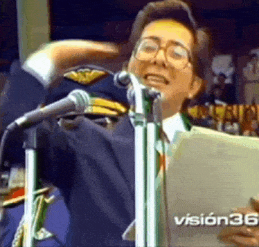 a man is singing into a microphone while wearing a military hat and glasses .