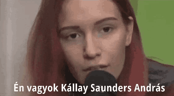 a woman with red hair is talking into a microphone and the words en vagyok kallay saunders andras are above her .