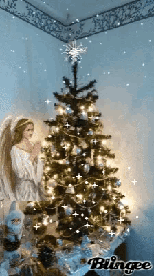 a blingee image of a christmas tree with an angel praying in front of it