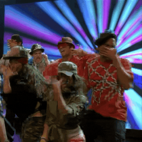 a group of people are dancing in front of a colorful screen
