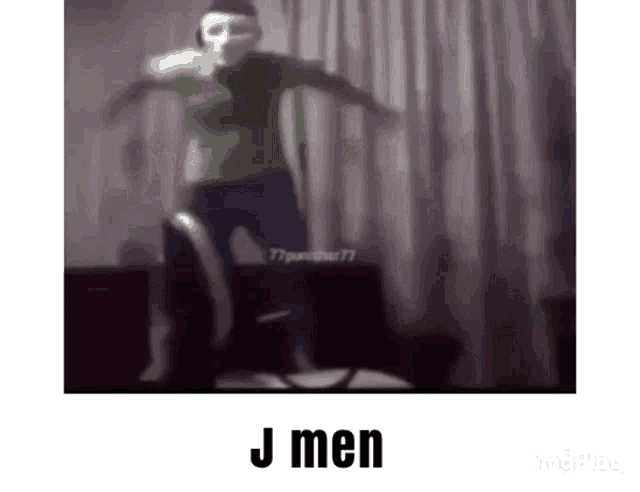 a man wearing a mask is dancing in a living room with the words j men written on the bottom .