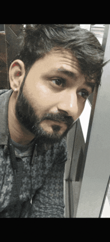 a man with a beard looks at the camera with a serious look on his face